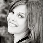 A black and white portrait capturing a smiling woman with long hair, exuding confidence.