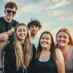 Happy young friends posing and smiling together at Avila Beach, California during a sunny day.